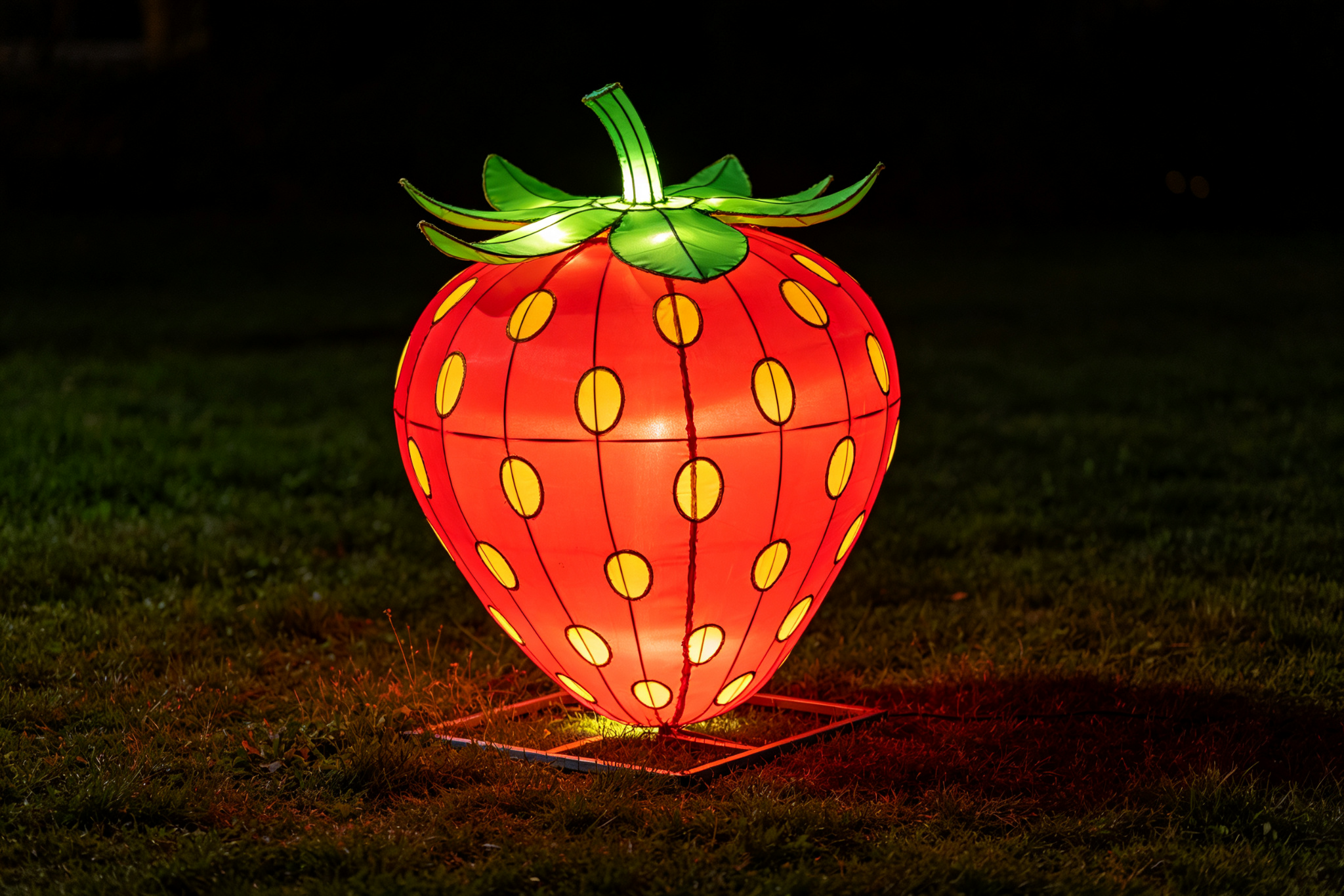 Red strawberry lantern on grassy field at night